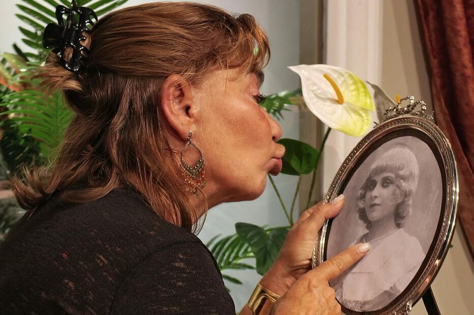 Mulher beija fotografia antiga em moldura oval, num gesto de carinho