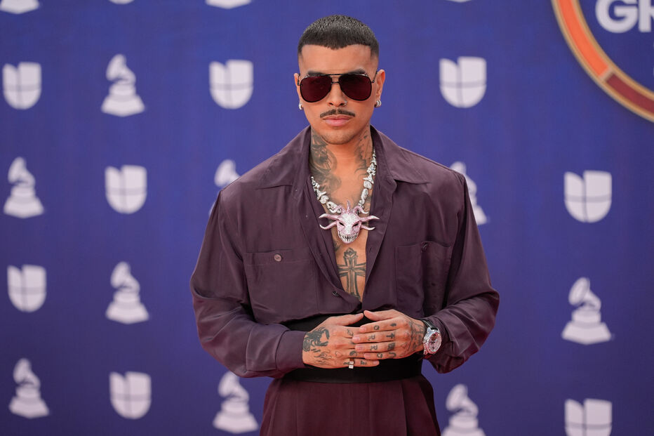 Rauw Alejandro posa no tapete de prémios com óculos de sol e colar de caveira