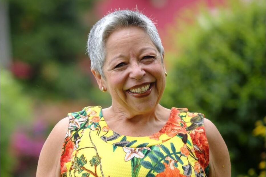 Mulher sorri com vestido floral em jardim