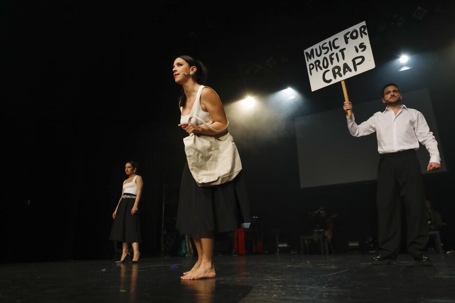Atores em palco com cartaz a dizer 