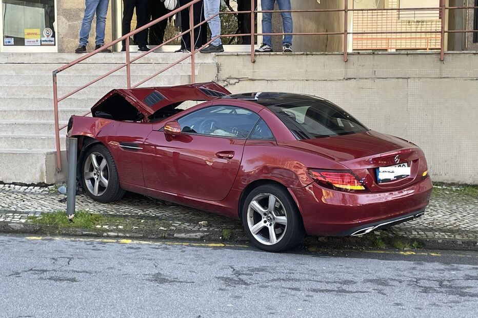 Um carro vermelho danificado estacionado junto a um edifício