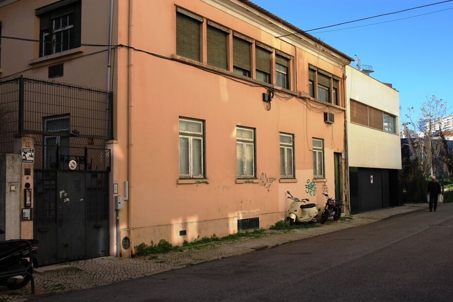 Rua calma em Lisboa com edifícios antigos, motas estacionadas e um homem a caminhar