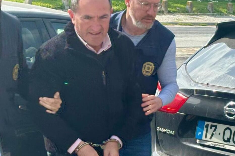 Homem detido e algemado é escoltado por dois agentes da polícia