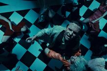 Num salão de baile, Frankenstein segura uma taça enquanto corpos jazem no chão