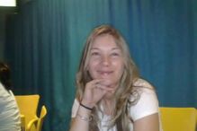 Mulher sorri com a mão no queixo num ambiente informal