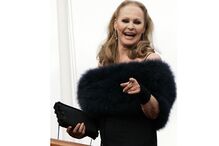 Ursula Andress sorri e aponta durante um evento