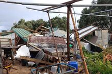 Estrutura metálica retorcida e destroços após evento climático