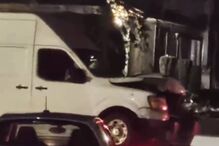 Colisão noturna entre uma carrinha branca e um carro cinzento