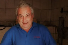 Retrato de um homem sorridente com uma camisa azul num espaço interior