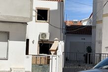Casa com janelas queimadas e fita da polícia indica investigação em curso
