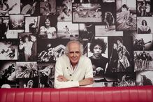 Tozé Brito fala sobre carreira na rádio, com imagens de músicos no fundo