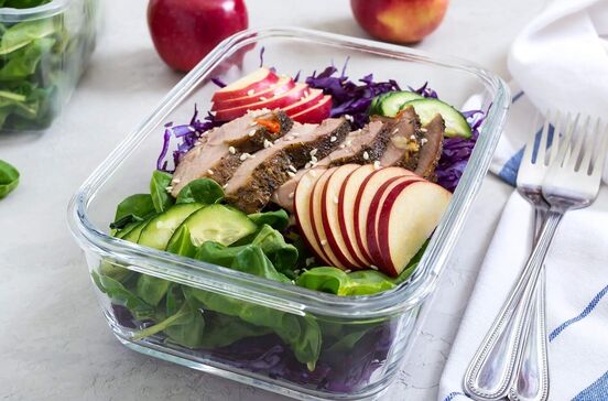 Refeição equilibrada numa marmita: carne, maçã, pepino e repolho roxo