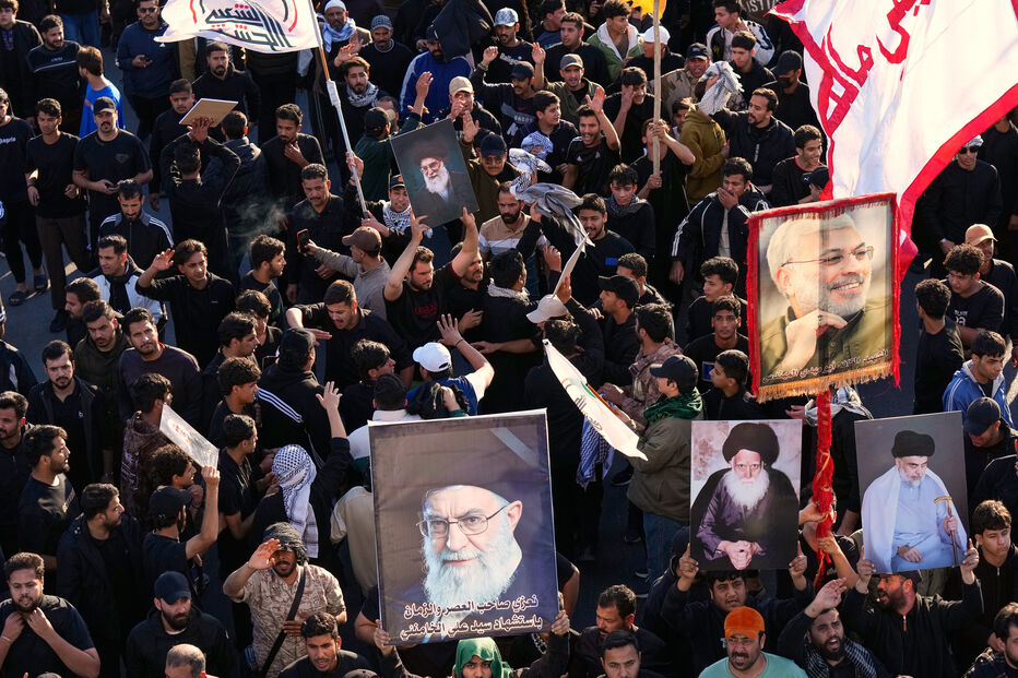Pessoas seguram fotos do líder supremo iraniano, Ali Khamenei, durante um funeral simbólico em Bagdá, no Iraque.