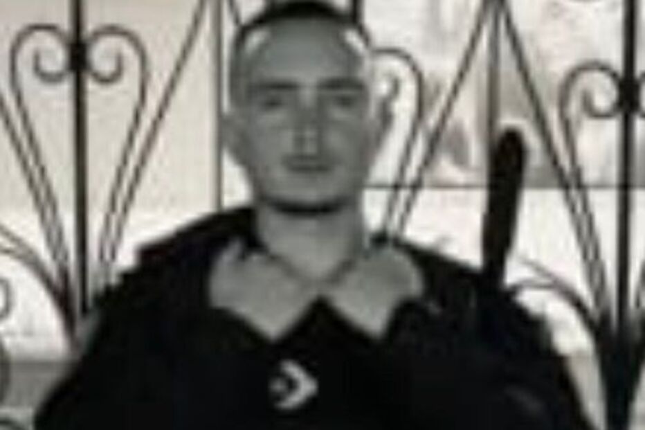 Homem posa com equipamento de segurança em frente a uma porta de metal decorada