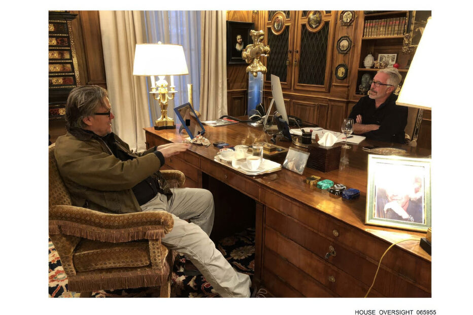 Steve Bannon num escritório, com outra pessoa, mesa de madeira e objetos pessoais