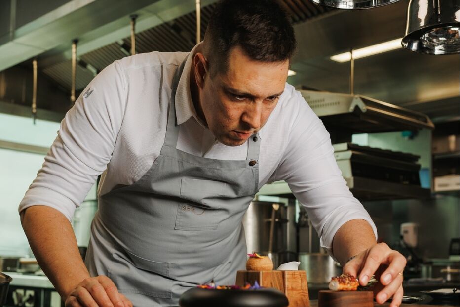 Chef prepara prato num restaurante com estrelas Michelin no Funchal.
