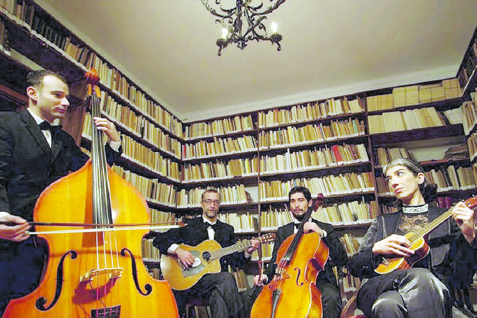 Grupo musical atua numa biblioteca com instrumentos de corda
