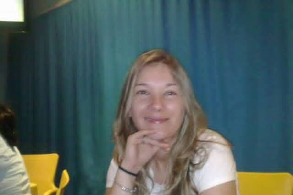 Mulher sorri com a mão no queixo num ambiente informal