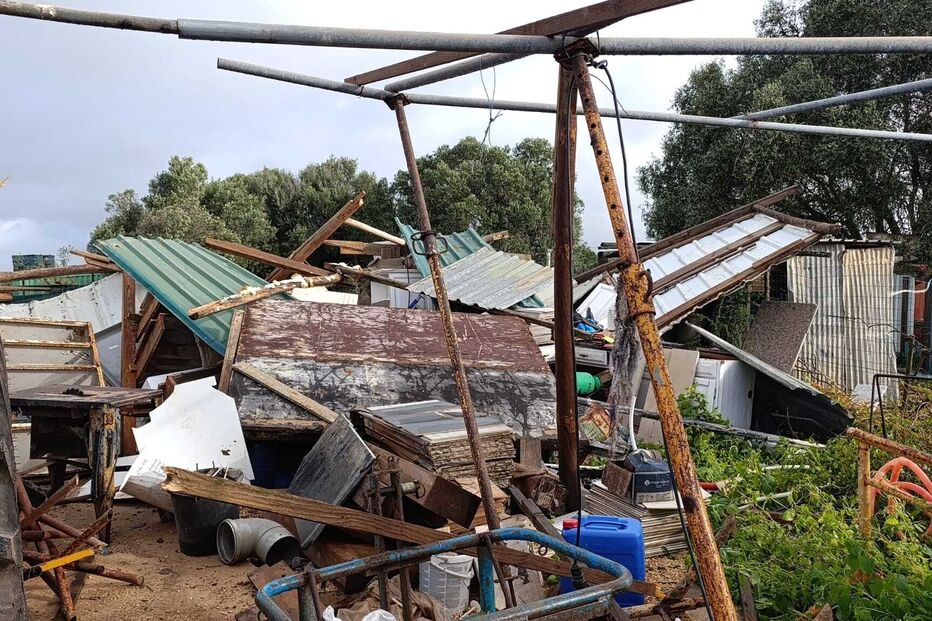 Estrutura metálica retorcida e destroços após evento climático