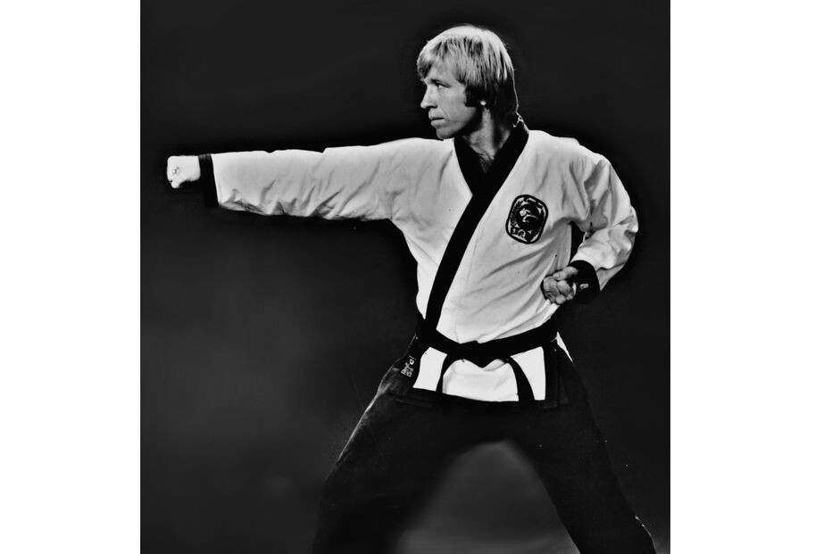 Chuck Norris mostra a sua forma física e atira um murro.
