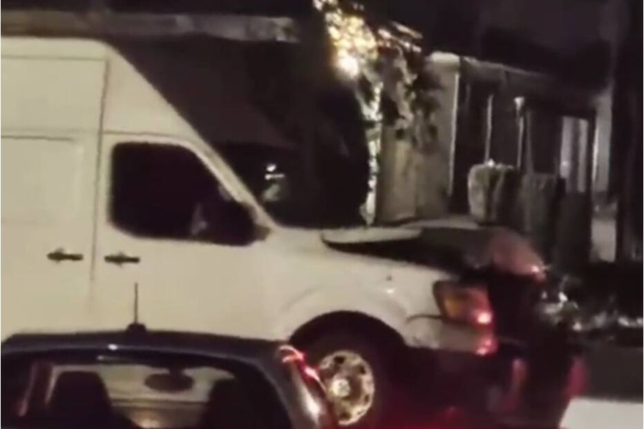 Colisão noturna entre uma carrinha branca e um carro cinzento