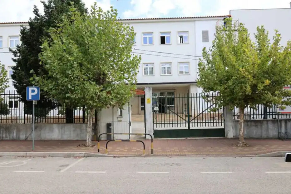 Edifício com árvores e sinal de estacionamento.
