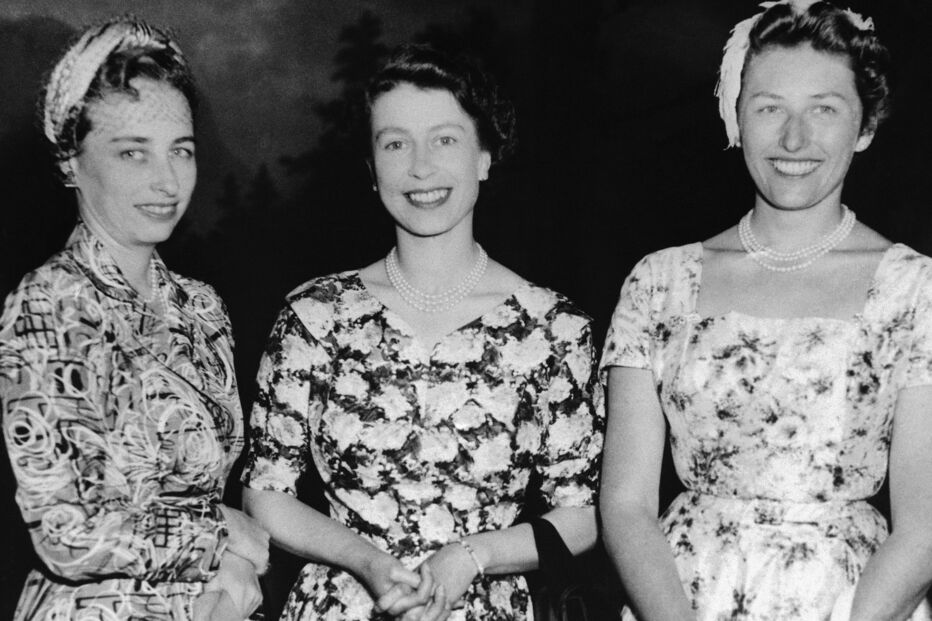Três mulheres sorridentes posam juntas, com destaque para a Rainha Isabel II