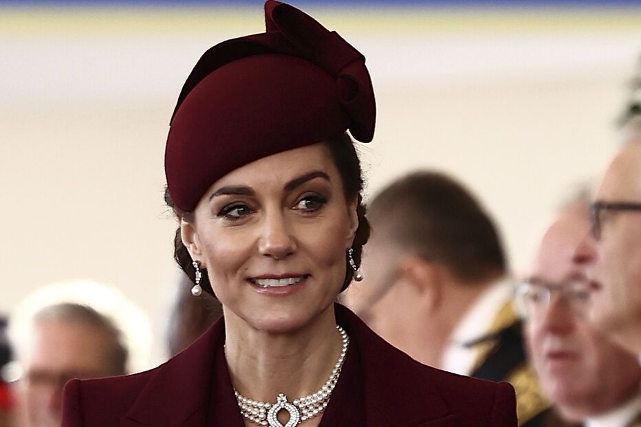 Kate Middleton surge elegante num evento, com um casaco e chapéu bordeaux
