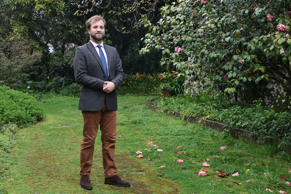Homem posa num jardim com camélias em flor