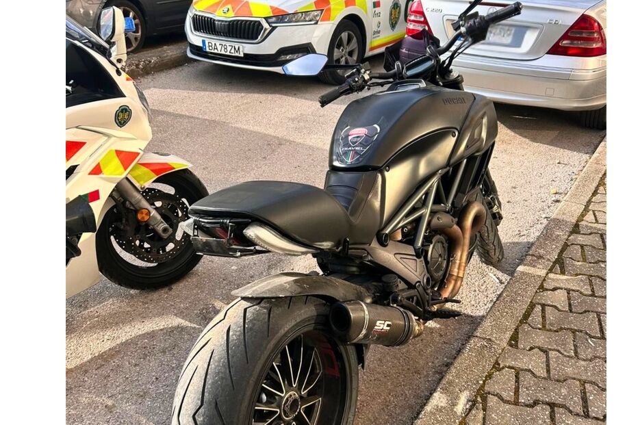 Motociclo da GNR estacionado na rua junto a outros veículos