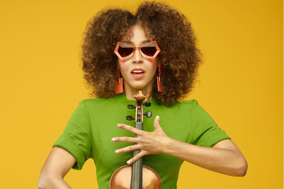 Mulher com óculos de sol e vestido verde segura um violino