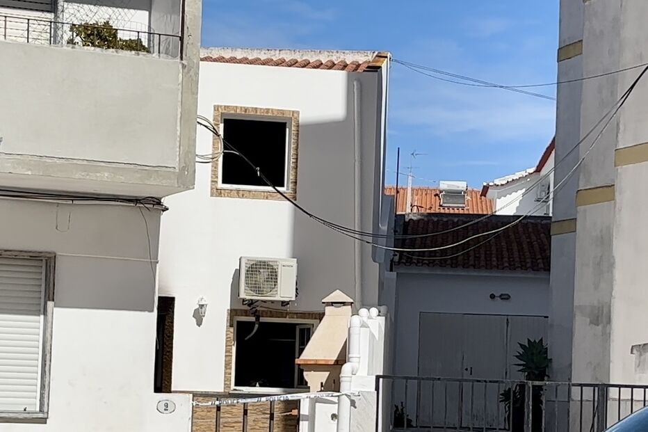 Casa com janelas queimadas e fita da polícia indica investigação em curso