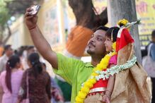 Menina indiana vestida como a deusa Durga ao colo do pai