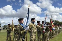 Militares fardados perfilados com boinas pretas e bandeiras em parada