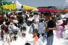 Pessoas celebram festival com espuma e guarda-sóis coloridos