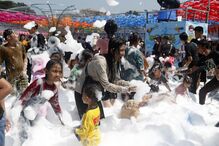 Pessoas divertem-se numa festa com espuma em ambiente aberto