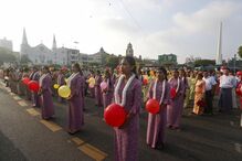 Pessoas reunidas numa rua com balões e vestes tradicionais