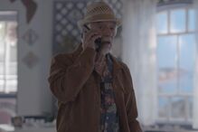 Homem ao telefone com camisa florida e chapéu