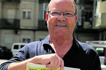 Homem exibe jornal com manchete sobre militante do PS detido por ataque à bomba