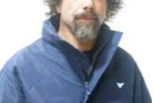 Homem com cabelo encaracolado e barba surge com casaco azul