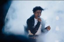 Michael Jackson canta num palco, com luzes e névoa