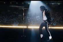 Michael Jackson atua num palco iluminado com uma multidão ao fundo