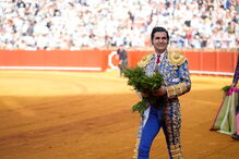 Um matador de toiros sorri com um ramo na mão na arena