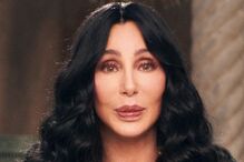 Retrato de Cher com um casaco preto e dourado brilhante