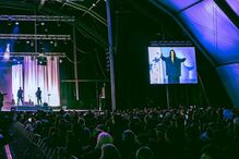 Concerto com artista no ecrã e banda no palco para uma multidão