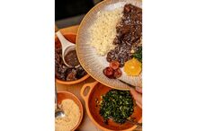 Prato de feijoada com arroz, laranja, couve e farofa