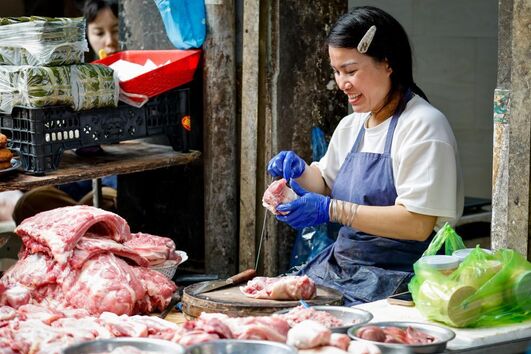 Mulher vende carne de porco num mercado Vietnamita
