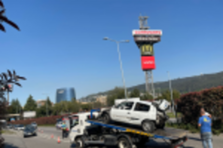 Um carro branco danificado é removido por um reboque após um acidente