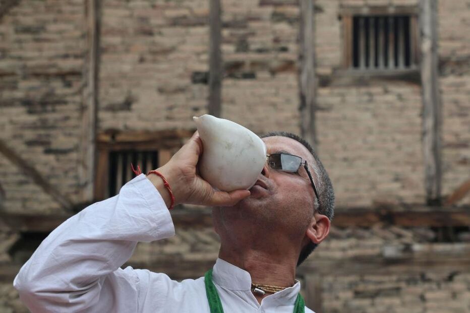 devoto hindu sopra uma concha durante uma procissão