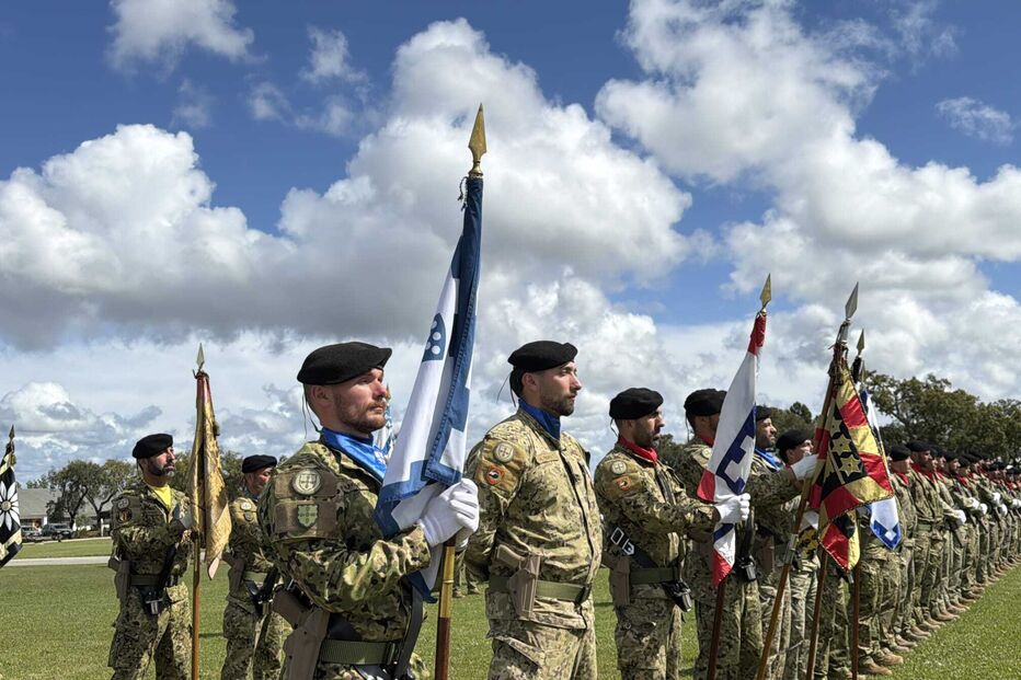 Militares fardados perfilados com boinas pretas e bandeiras em parada